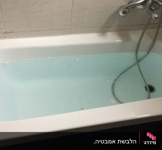 אמבטיה עם מים וברז מקלחת על הקיר